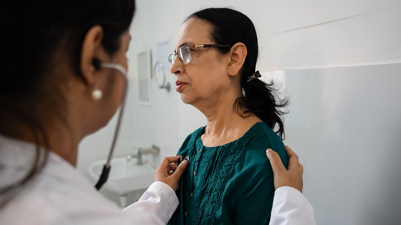 Doctor listening to female patient's heart